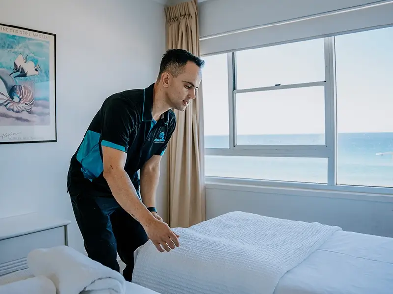 Ninja Hands cleaner making a bed in a beachside apartment